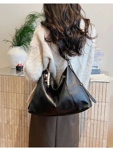 Sac hobo noir en cuir avec perles de bois décoratives et coutures sur la bandoulière