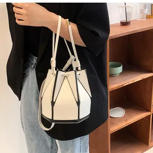 Detail of white leather bucket bag with black geometric lines and metal hardware