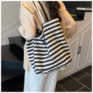 Close-up of stylish black and white striped canvas tote bag with metal logo detail