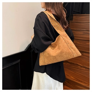 Detail of brown suede tote bag featuring metallic gold rivets and studs on strap and edge