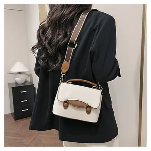 Détail du sac bandoulière en cuir grainé crème et marron avec une bandoulière réglable