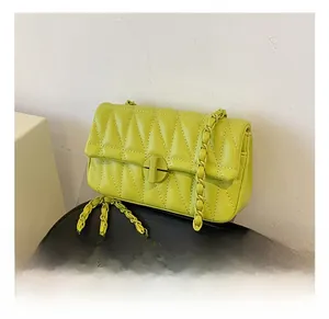 Detail of neon quilted crossbody bag featuring metal chain strap and twist-lock closure