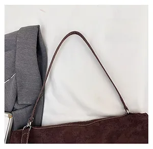 Detail of dark brown suede shoulder bag with silver metal buckle and white stitching