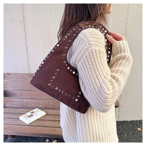 Détail du sac à bandoulière en daim marron foncé avec rivets argentés de style urbain