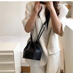 Detail of a black origami bucket bag showing geometric folds on a crossbody strap