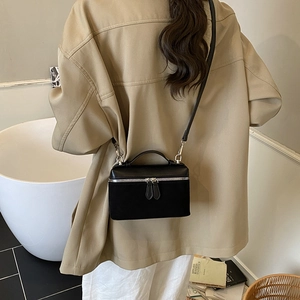 Chic black crossbody square bag with leather patchwork shown on a model in a modern room