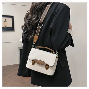 Détail du sac à main blanc crème avec bordure marron et texture cuir grainé de qualité