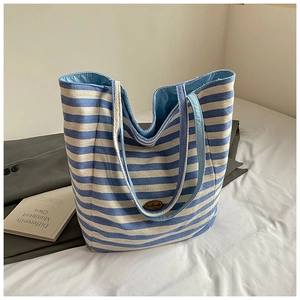Detail of blue and white striped canvas tote bag with handmade logo on bed