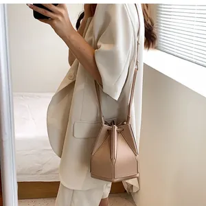 Detail of light beige geometric bucket bag featuring unique multi-panel leather stitching