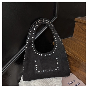 Détail du sac à main en daim noir avec clous argentés et poignée ovale élégante