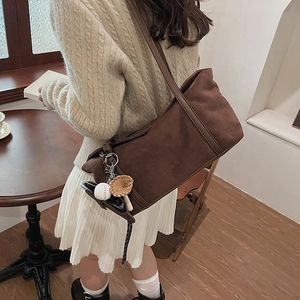Vintage brown suede tote bag with baseball charm on a shoulder worn by a model