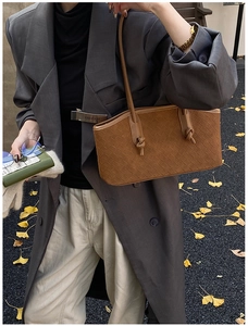 Detail of a brown woven texture tote bag with knot handle accents on an autumn background