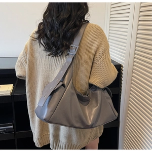 Detail van grote grijze tote bag met brede riem en gesp op een beige gebreide trui