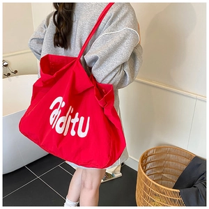 Gros plan d'un grand sac cabas en toile rouge avec lettrage blanc et intérieur spacieux