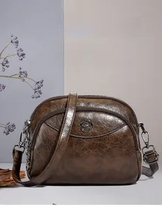 Close-up of soft brown leather bag with kangaroo metal logo and multi-layer zippers