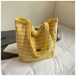 Detail of a large capacity yellow and white striped canvas tote bag with a metal logo
