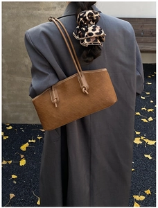 Detailed close-up of dark brown suede shoulder bag with woven texture and knotted straps