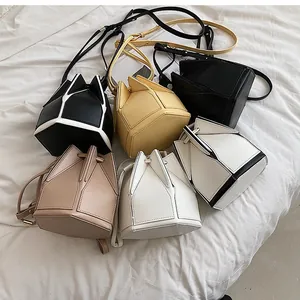 Multiple colors of geometric folded PU leather bucket bags on white fabric