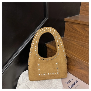 Détail du sac à main en daim marron avec rivets métalliques et poignée ovale évidée