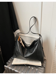 Détail d'un sac cabas rétro en cuir noir vieilli avec pendentif à pampilles perlé