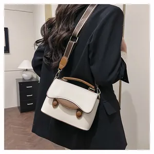 Vue détaillée du sac bandoulière en cuir crème avec poignée marron et large bandoulière