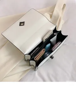 Internal view of white leather crossbody bag showing spacious compartments for cosmetics