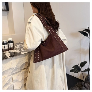 Detail of dark brown suede tote bag with three rows of metallic rivets on the side