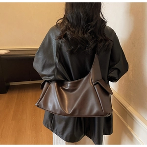 Détail du grand sac hobo marron foncé en cuir souple porté à l'épaule par un mannequin