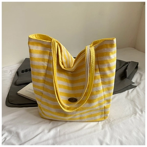 Detail shot of a yellow and white striped canvas tote bag with a Handmade leather patch