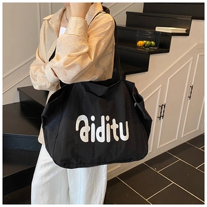 Détail du grand sac cabas en toile noire avec lettrage blanc sur la face avant
