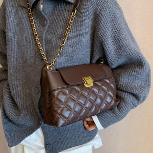 Sac à bandoulière matelassé marron foncé avec chaîne dorée sur gilet en maille grise