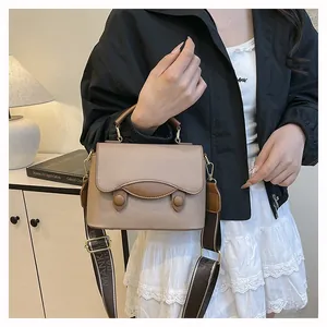 Détail du sac à main en cuir kaki avec surpiqûres et large bandoulière tissée