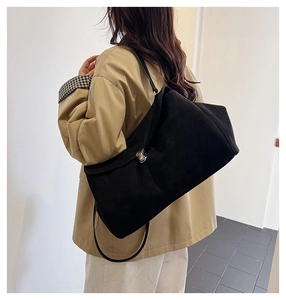 Detail of black faux suede shoulder bag featuring a sleek silver metal twist lock closure