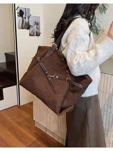 Detail of plush faux shearling tote bag with brown leather strap and gold hardware