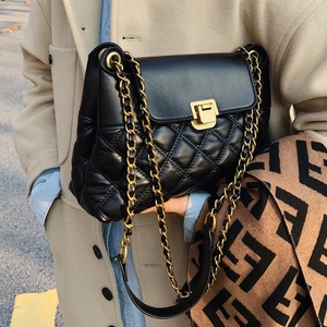 Sac à bandoulière matelassé noir avec chaîne dorée sur fond de manteau en laine beige clair