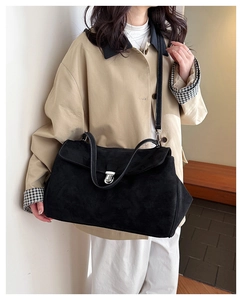 Detailed view of black suede shoulder bag with silver buckle and white stitching detail
