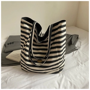 Close-up of black and white striped canvas tote bag with retro copper metal nameplate