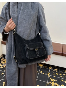 Détail du sac bandoulière noir avec surpiqûres contrastées et boucle en métal doré