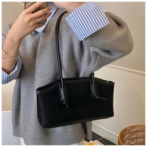 Close-up of black woven shoulder bag with unique knot detail on slim leather straps
