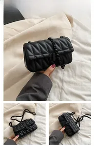 Detail of black quilted crossbody bag with matte round buckle and faux leather chain strap
