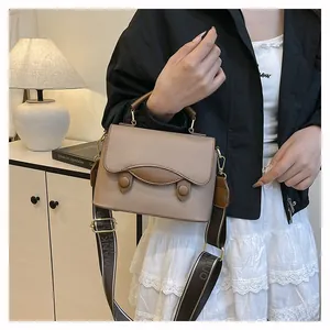 Détail du sac beige en cuir texturé avec large bandoulière en tissage jacquard