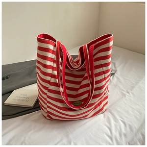 Detail of red and white striped canvas tote bag with retro handmade metal plaque detail
