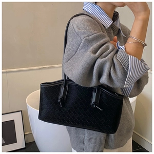 Detail of black woven leather tote bag featuring a decorative knot on the shoulder strap