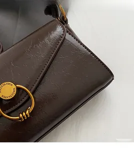 Close-up of smooth oil wax leather texture and handmade stitching on dark brown handbag