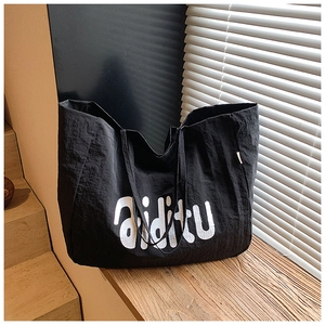 Détail d'un grand sac cabas noir avec lettrage blanc sur tissu en nylon texturé