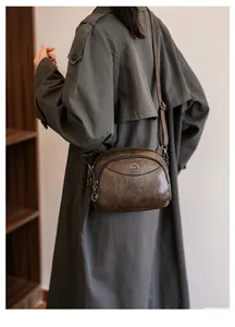 Rear view of model wearing a vintage brown faux leather crossbody bag with double zippers