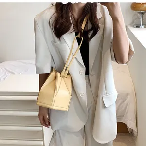 Model wearing a yellow folding bucket bag with elegant pleated design and thin strap