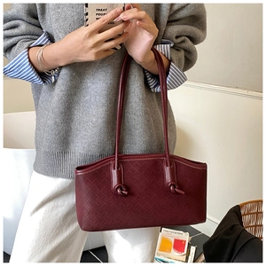 Detail of burgundy woven leather shoulder bag with decorative knot and texture