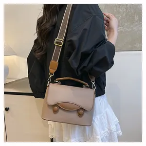 Détail du sac à bandoulière en cuir grainé avec une large sangle tissée tendance
