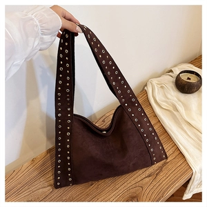 Detailed macro of dark brown suede tote bag featuring metallic rivets on handle strap